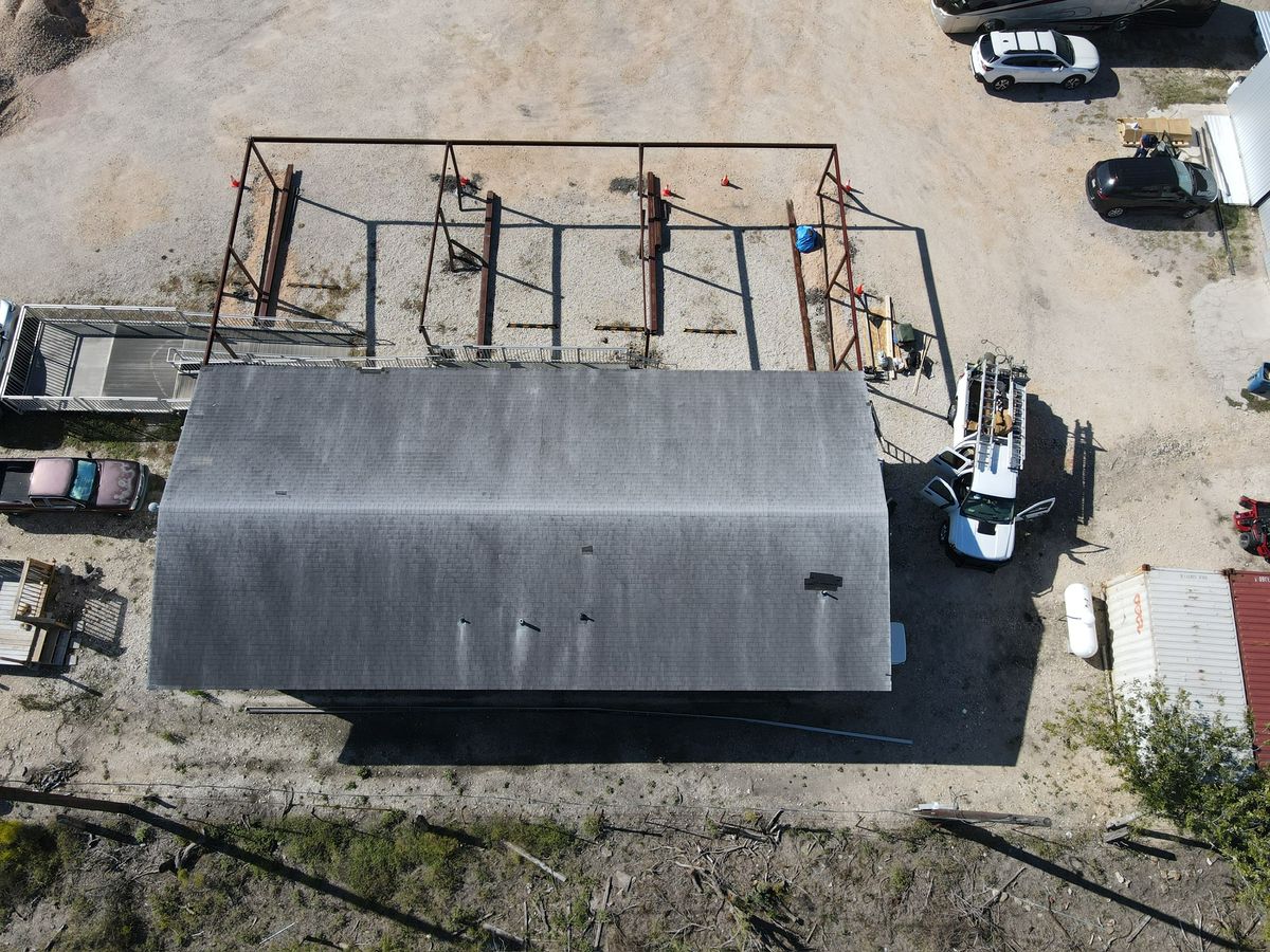Aerial view of a finished dark shingle roof on a rural barn